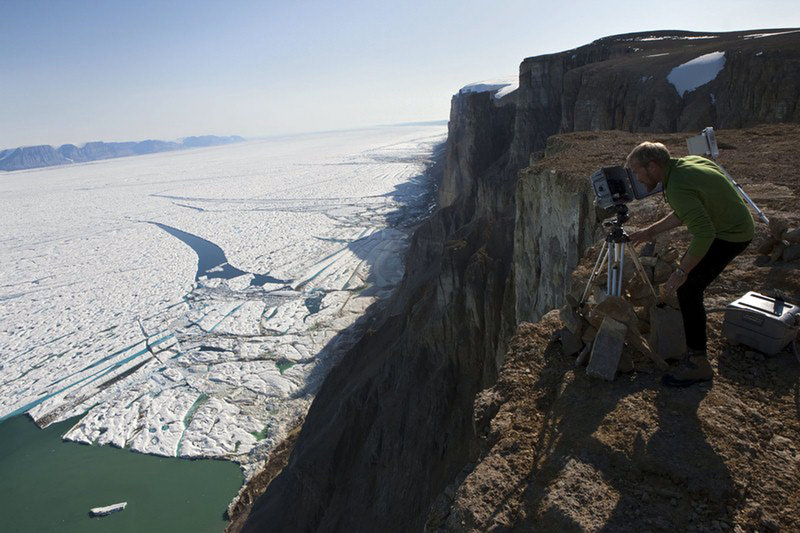 In a July 6, 2009, photo made available by Greenpeace, researcher Jason Box adjusts a time-lapse camera on the southeast side of Petermann Glacier, one of Greenland’s largest and most northerly glaciers. A 100-square-mile iceberg broke off the glacier last week.
