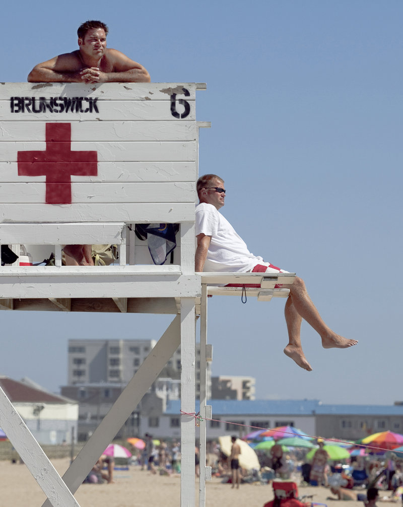 Chief lifeguard Keith Willett, right, and lifeguard Wes Rhames keep an eye on swimmers Wednesday at Old Orchard Beach.