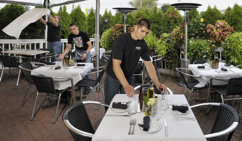 Najib El Karmach, left, Huba Mozes and Atanas Dinkov set the tables on the terrace, one of the dining areas at Angelina’s Ristorante and Wine Bar in Ogunquit, in anticipation of a bustling dinner hour.
