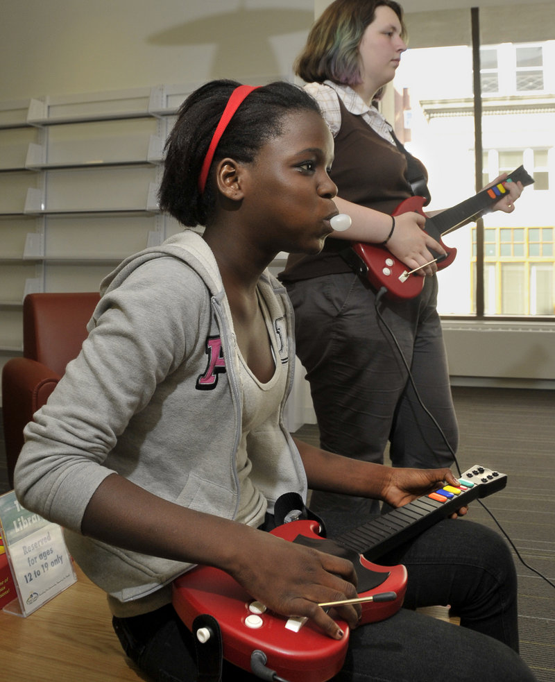 Christina Mahounou, 13, left, and Sasha Leppanen, 13, play Guitar Hero III during game night Wednesday at the Portland Public Library.