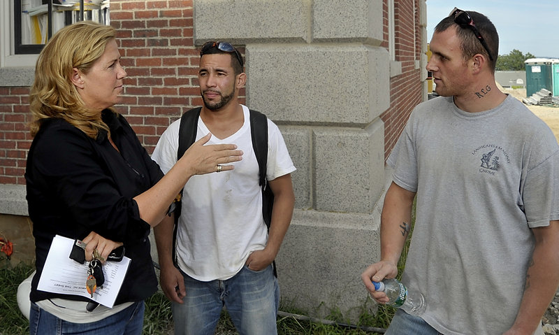 Margo Davies, who created a temp agency that specializes in finding work for felons, talks with employees Leonardo Tavares, center, and Royce Guptill at the end of a workday.