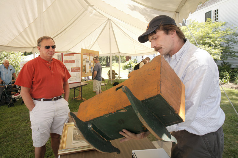 Jay Boschetti appraises a cradle owned by Ray Harris, left, and his wife Maureen during the festival. Boschetti owns Steam Mill Antiques in Bethel.