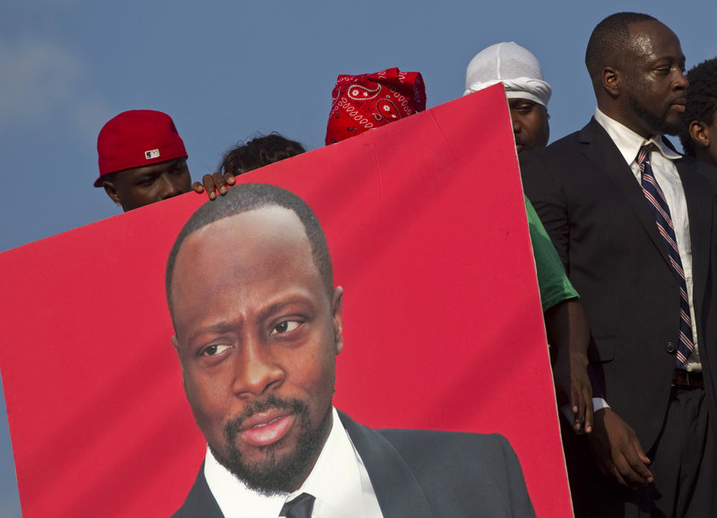 A supporter holds a portrait of Haitian-born singer Wyclef Jean, a candidate for president. Haiti’s “future is dual citizenship,” he says.