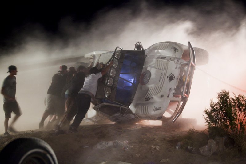 Workers push an overturned off-road truck upright Sunday, after the driver took a jump at high speed and ran into a crowd of spectators at a Lucerne Valley, Calif., race Saturday.