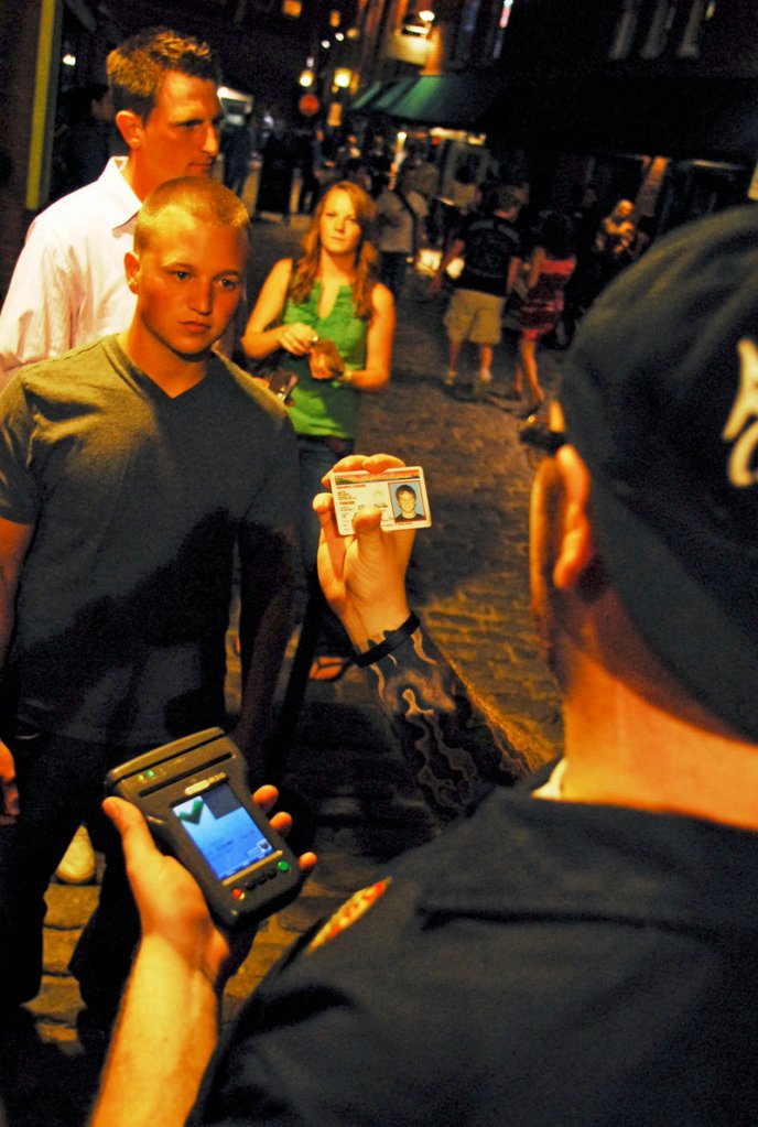 Oasis doorman Zack Swander, right, checks IDs at about 11 p.m. on the night of Friday, Aug. 13. Oasis and 51 Wharf are using ID scanners that flag any patrons who have previously caused problems at the bars.