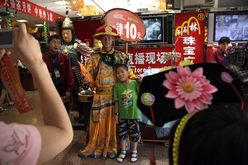 A man dressed as a Chinese emperor poses for photos Monday to promote a shop in Beijing. Japan lost its place as the No. 2 economy in the second quarter as receding global growth sapped its momentum.