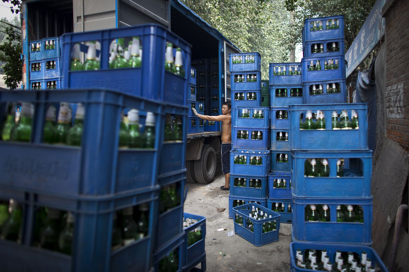 A worker takes a break near a truck Tuesday while loading packs of beer bottles in Beijing. China’s 1.3 billion people had an average income of $3,600 last year.