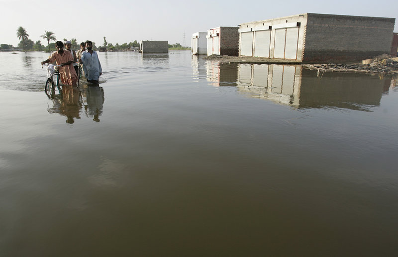 Flood survivors walk through high water near Multan, Pakistan, on Tuesday. The World Bank said it will redirect $900 million of its existing loans to Pakistan to help in flood recovery, as the U.N. warned that many of the millions affected by the disaster have yet to get any aid.