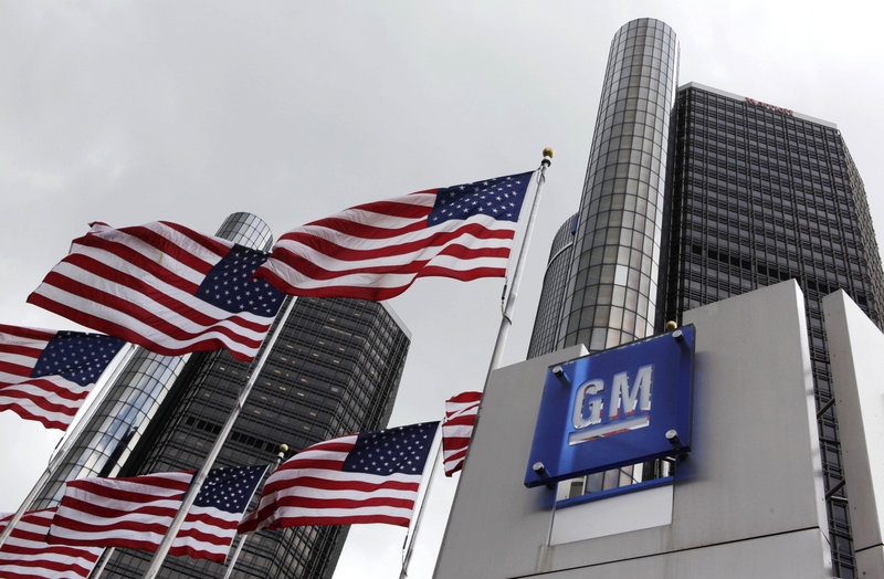 U.S. flags fly at General Motors headquarters in Detroit. GM, 61 percent owned by the federal government, didn’t disclose the number of shares that will be sold or the price.