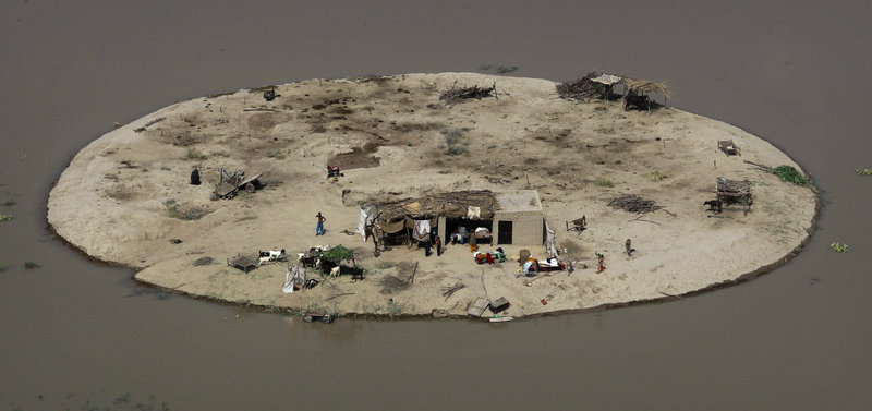 A family is stranded on its farm by floodwaters Thursday near Bachel in Sindh Province, Pakistan. Amid criticism that the international community hasn’t done enough to assist flood victims, the United States, Germany and Saudi Arabia announced new pledges of aid.