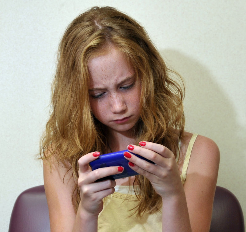 McKenna Wood, 12, plays with her mother’s iPhone while waiting for an eye exam. She says she’s learned not to overdo it with modern digital devices.
