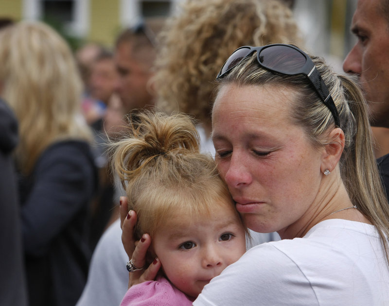 Pam Maxon of Wells holds her daughter Payton, 2, while listening to the names of 65 fallen soldiers being read before the start of the run.