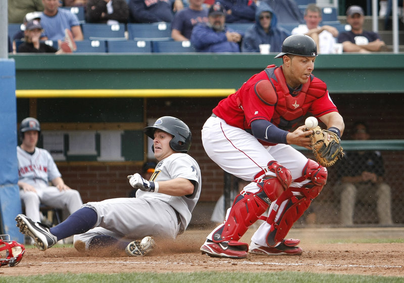 Trenton's Matt Cusick scores on a squeeze bunt as Portland catcher Luis Exposito loses his grip on the ball in the seventh inning Sunday afternoon at Hadlock Field. The Sea Dogs beat the Thunder 7-6 in 11 innings, closing their six-game homestand with a 2-4 record.