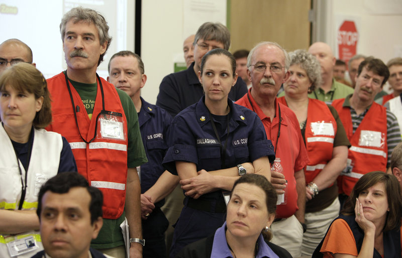On June 12, BP employees and members of the Coast Guard at the Houma, La., Joint Information Center listen to BP Chief Operating Officer Doug Suttles speak about the Deepwater Horizon oil spill. BP and Coast Guard employees also sat side-by-side at a command center in Robert, La.