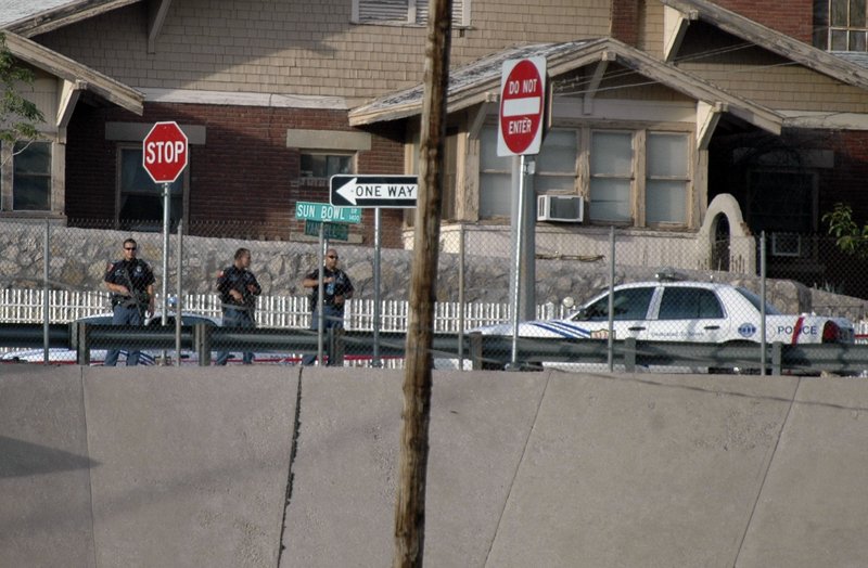 El Paso, Texas, police officers look out into the border city of Ciudad Juarez, Mexico, after a gunbattle erupted in Ciudad Juarez Saturday. A stray bullet from the gunfight crossed the Rio Grande and lodged in a door frame at a university building.