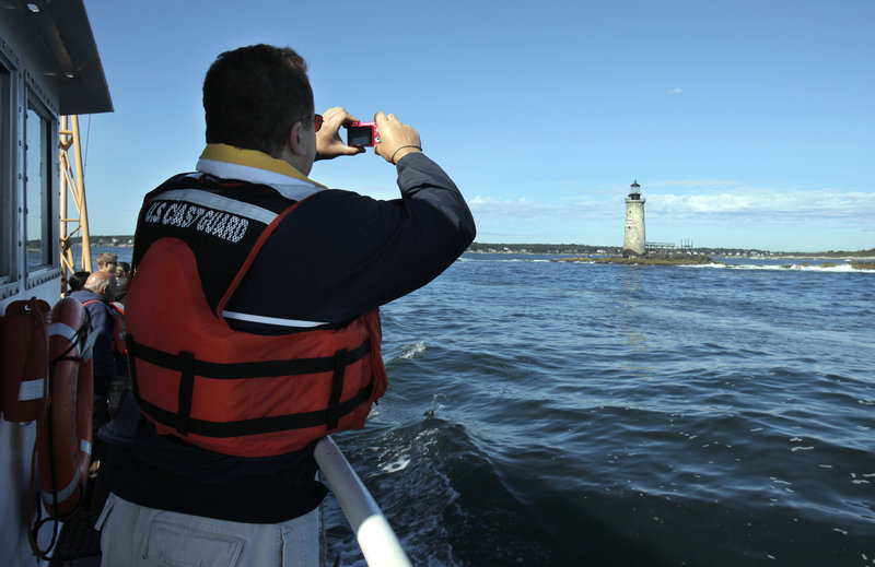 Scott Raspa of Cape Elizabeth, a registered bidder, takes a photo of Ram Island Ledge Light on Thursday. He said the mystery and history would make it interesting to own a lighthouse.