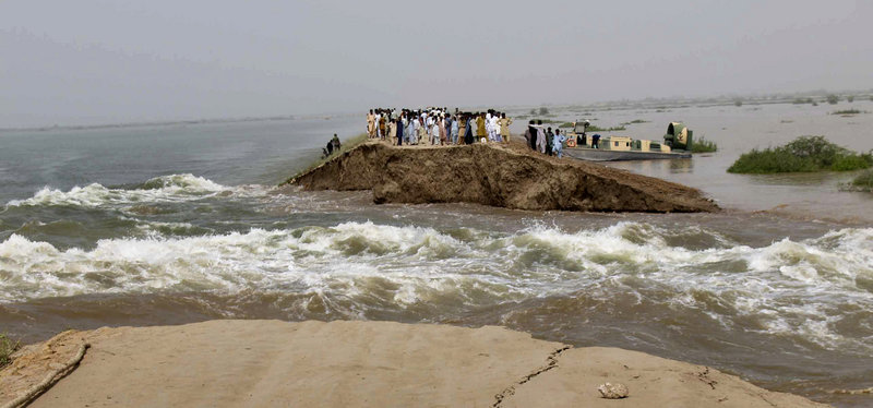 Pakistani villagers stand on the remains of an embankment washed away by heavy flooding near Hyderabad on Thursday. Some 8 million people are in need of emergency aid, but the Taliban doesn’t believe foreigners are there to help them.
