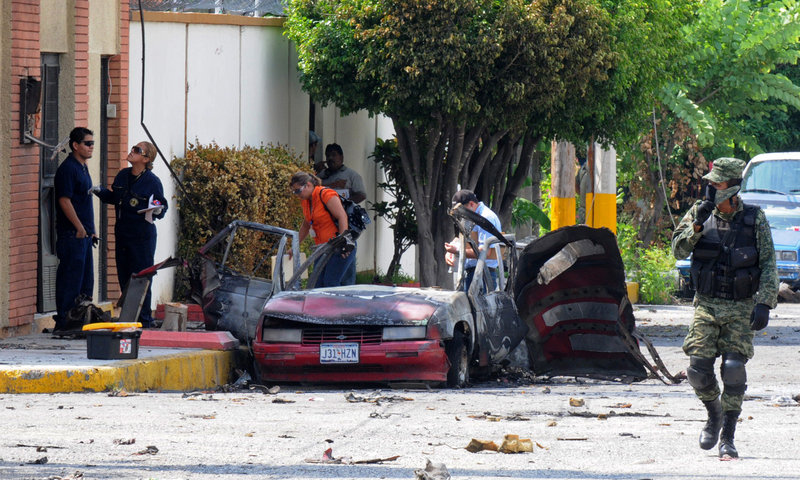 Investigators probe the site of one of two vehicle explosions Friday in Ciudad Victoria, Mexico, in a northern state where officials are also investigating the massacre of 72 Central and South American migrants. Nobody was injured in the explosions.