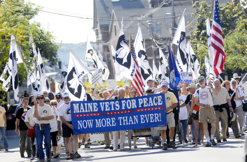 A throng of flag-bearing Veterans for Peace are gathered around their banner as they march through the Old Port Sunday.