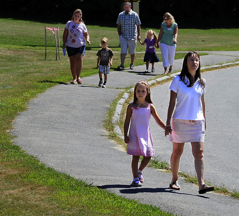 Olivia Bryant, 5, walks to school from the parking lot with her mother, Erica Bryant, as other parents and children follow Monday during the first day of kindergarten and orientation at the Narragansett School in Gorham.