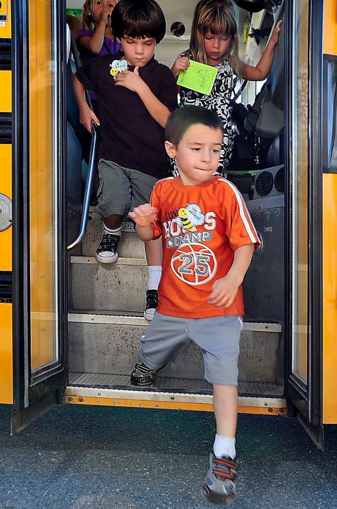 Joseph Cowan, 5, steps off the bus with fellow kindergartners Monday at the Narragansett School. Behind him are Shane Johnson, left, and Faith Connelly.