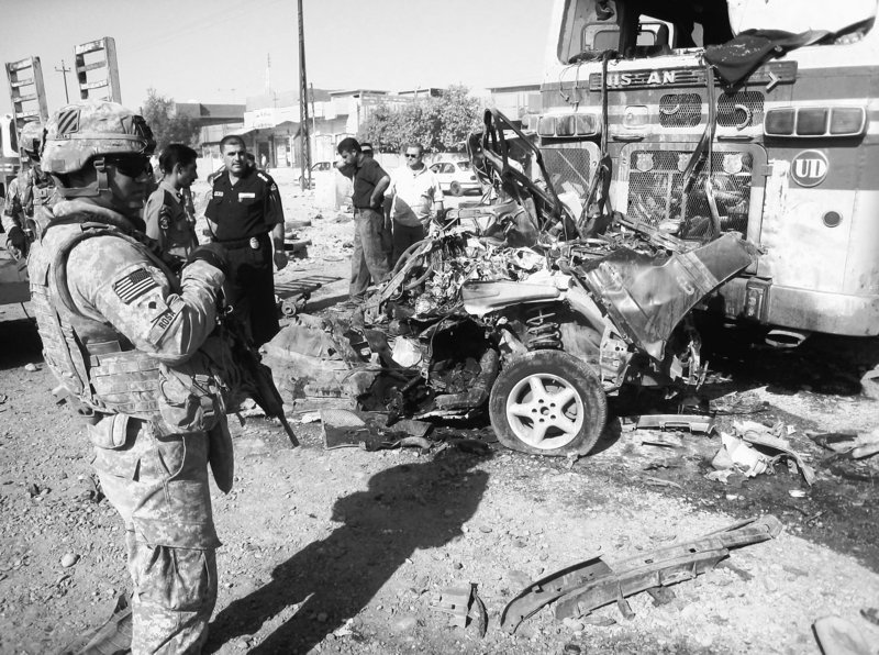 U.S. troops and Iraqi police inspect a bomb-damaged police vehicle in this Aug. 25 file photo after a series of terrorist attacks on Iraqi forces.