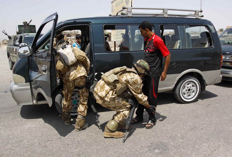 An Iraqi policeman searches a bus as another searches a man at a check point in Basra, Iraq on Wednesday. The U.S. has shifted the focus of the remaining 50,000 American troops from combat operations to preparing Iraqi security forces to protect the country on their own.