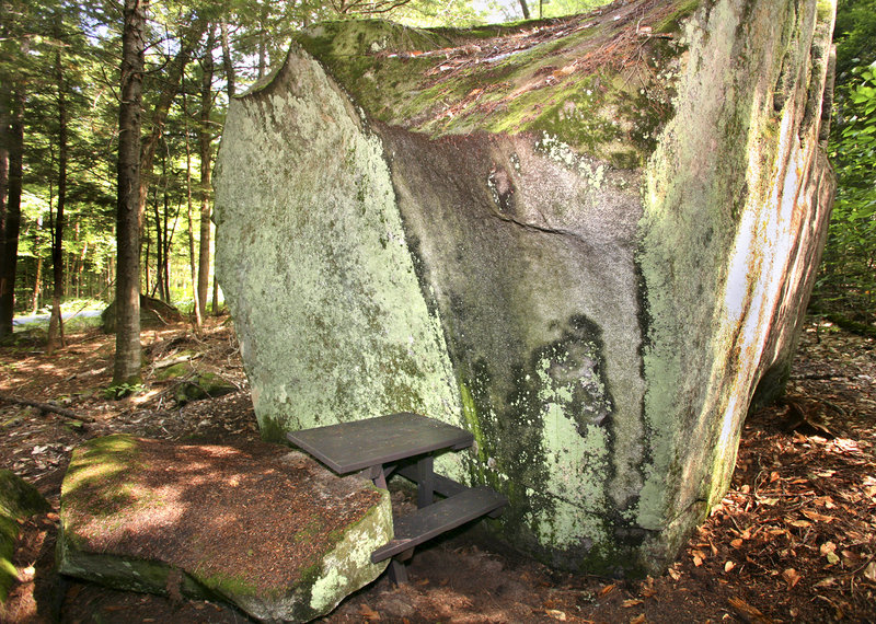 A finished table is dwarfed by a glacial erratic. Wade Kavanaugh is placing the tables in such places as to put people physically closer to the things they come to the park to enjoy.