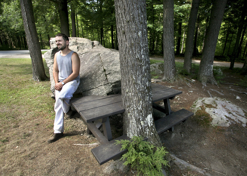 Wade Kavanaugh is working on a series of picnic tables that interact with the natural terrain at Peaks-Kenny State Park. He poses with a completed table near the entrance to the park.