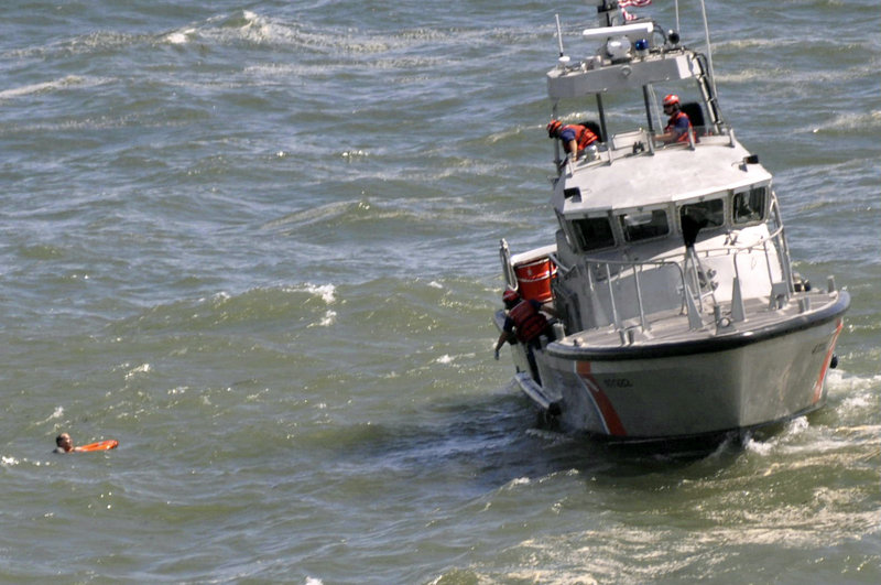 Rescue workers aboard a U.S. Coast Guard boat toss a line to man who'd been swept into the ocean off Acadia National Park last year by waves caused by Hurricane Bill.
