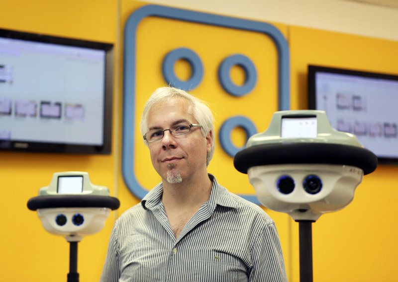 Anybots founder and CEO Trevor Blackwell, with two QB Anybots, says the $15,000 robots can inspect warehouses or factories remotely or provide tech support.