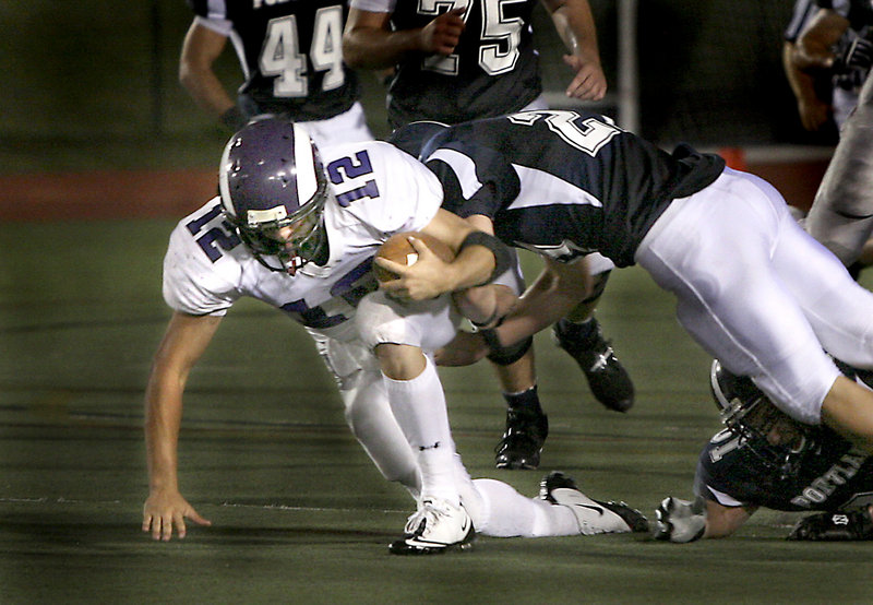 Deering quarterback Jamie Ross pushes forward for extra yardage Friday night while being tackled by Caleb Kenney of Portland in their Western Class A opener at Fitzpatrick Stadium. Ross scored a touchdown with 14 seconds remaining to give the Rams a 21-14 victory.