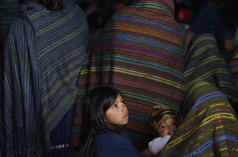 Guatemalan children attend a funeral Mass in Santa Maria Ixtahuacan on Sunday. A tropical depression saturated the ground and set off more than a dozen mudslides.
