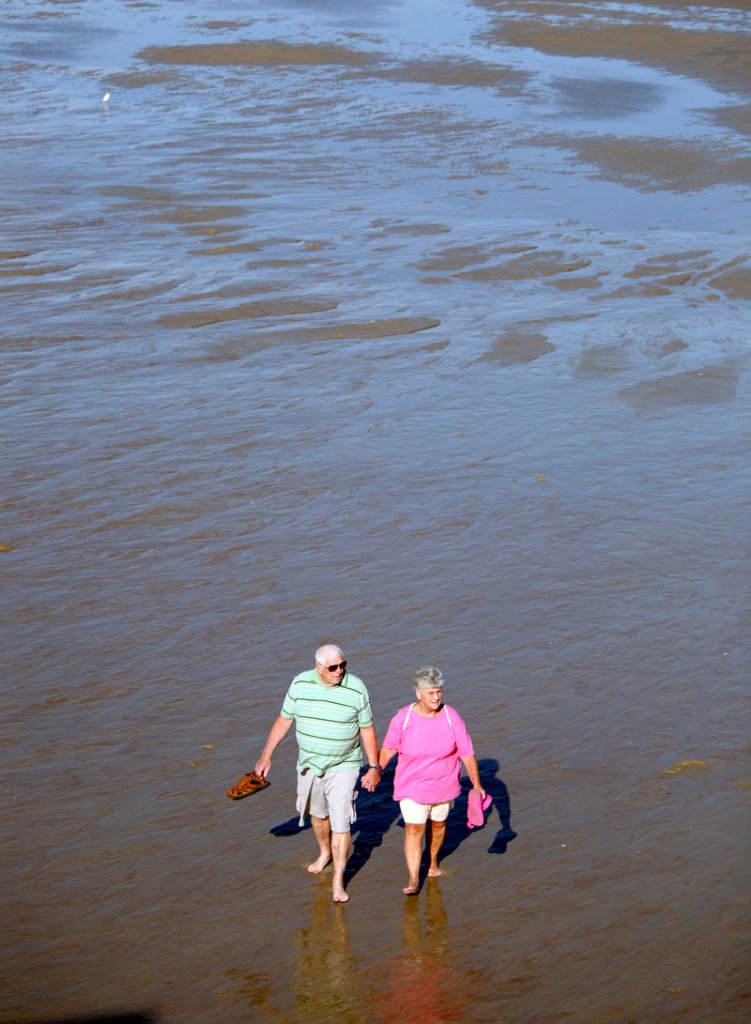 Joe and Joyce Breau of South Portland walk Old Orchard Beach at low tide Monday. They were there to enjoy pier fries and to watch tourists before they left for the season.