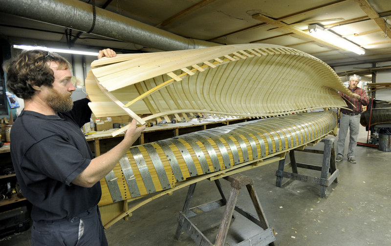 Canoe builder Jonathan Minott helps Jerry Stelmok, owner of Island Falls Canoe, lift a new canoe off its mold for continued construction. The molds for a canoe designed in the late 1880s still sit in Stelmok’s workshop.