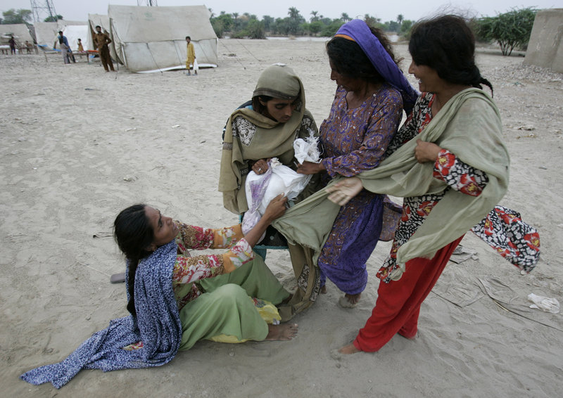 Pakistani women struggle for possession of a package of relief goods thrown from a truck near a camp for people displaced by floods in Punjab province on Wednesday. People in the camp have very few personal belongings and are relying on aid donations.
