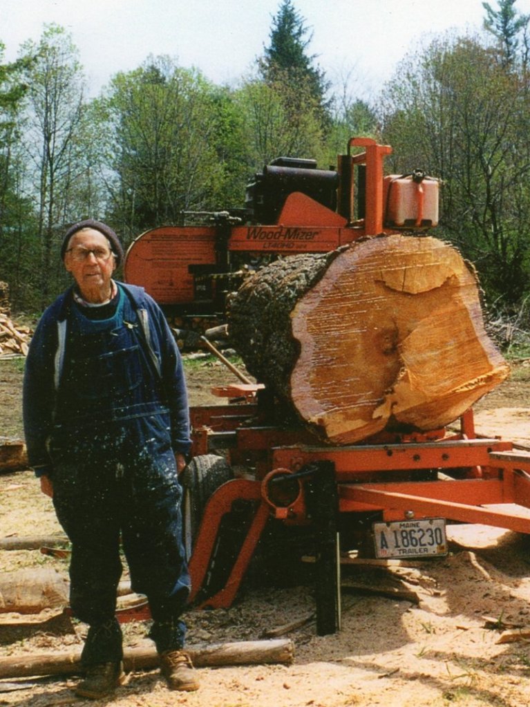 Emil Dunnell poses on his wood lot with a log ready to be sawed into lumber. “He got out of the land as much as he possibly could,” said a grandson, Brian Dunnell.