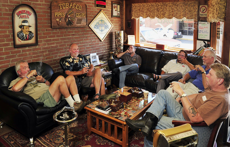 Dan Ducharme, owner of Dad’s Cigar Parlor and Tobacco Shoppe in Biddeford, is surrounded by customers enjoying the indoor smoking room with pipe and cigars. Left to right are Daniel Ahern, lighting a pipe, while Dave Colclough, DuCharme, Dale Berube, John Brady and Paul Brake partake of premium cigars in the smoking parlor section of the business. The display cases are in the rear of the store.