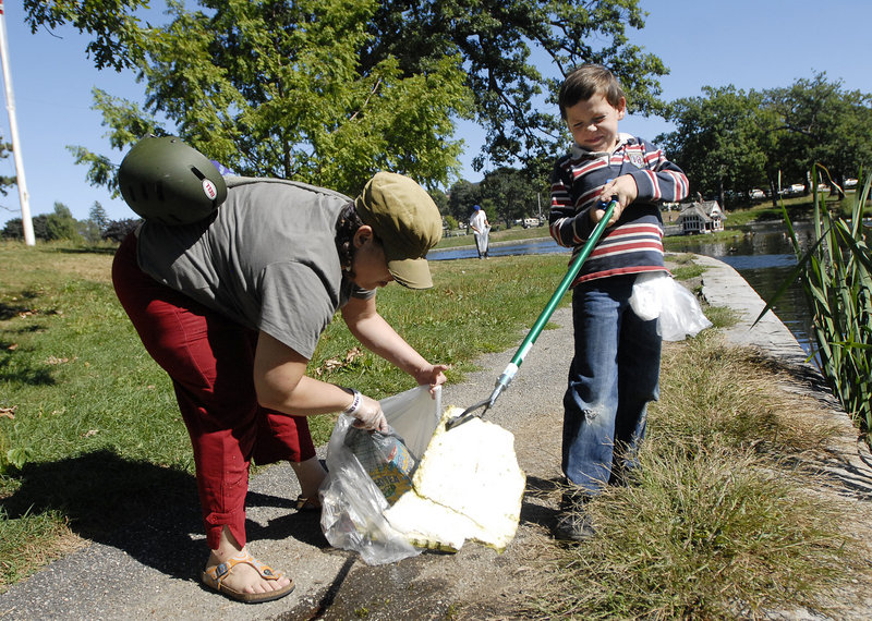 Julin Chapman, 7, helps his mother, Kathryn Irons, of Portland pick up debris at Deering Oaks in Portland Saturday, as part of the 9/11 National Day of Service.