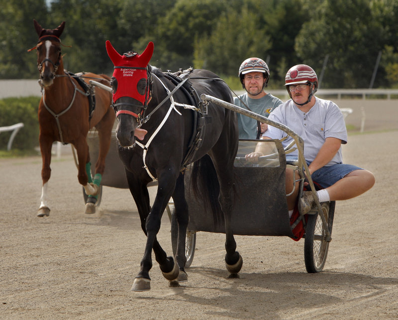 Reporter Ray Routhier, left, drives a jog cart around the track at Scarborough Downs with trainer Dick Robertson Jr.