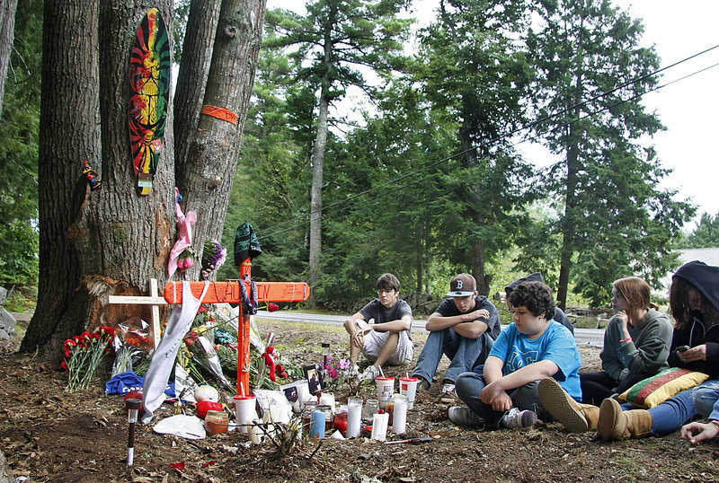 Sophomore Chris “Stumpy” Vaccaro, center in blue shirt, and other friends of Christian Lumenello of Ogunquit and Austin Dykes of Wells spend time Monday at the site of the crash that killed both students on Tatnic Road in Wells early Saturday morning.