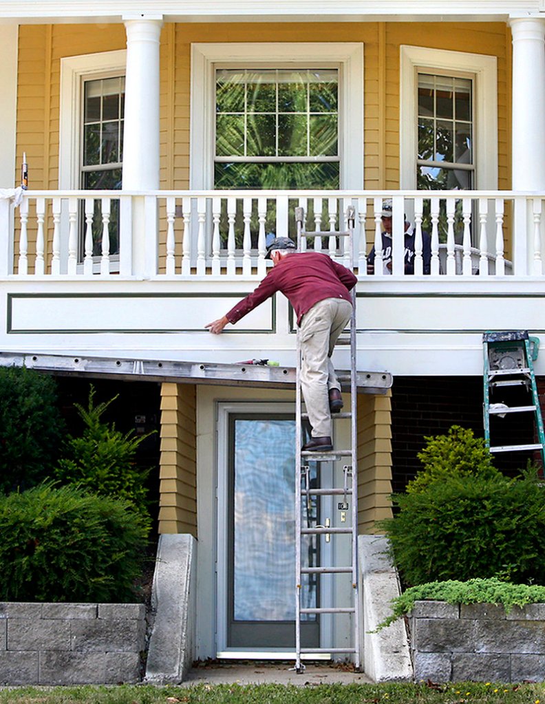 Rob May of Classic Painting and Wall Covering smooths out the caulking on a wraparound porch Tuesday at a house on Munjoy Hill in Portland. May said he is scraping, sanding and caulking the front of the home and expects to finish the work by the end of the month.