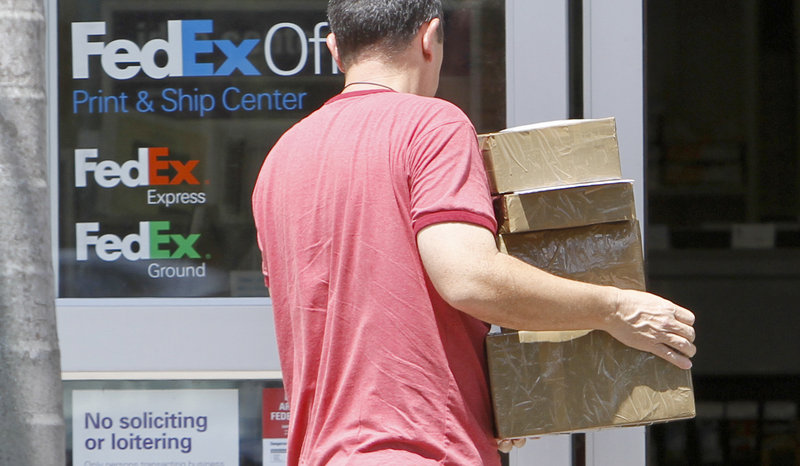A customer enters a FedEx office in Doral, Fla., loaded with packages. The company, based in Memphis, Tenn., reported Thursday that it earned $1.20 per share in the fiscal first-quarter that ended in August, compared with 58 cents per share a year ago.