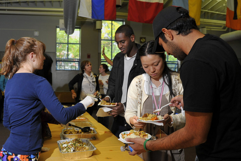 Volunteers from USM serve a variety of Middle Eastern and Indian food at the Eid celebration to mark the end of Ramadan, an event held at the university’s Woodbury Campus Center in Portland on Friday. Zag Alanjari, right, spoons a special sauce over the plate of Fumino Shiobara as Guled Ilmi, center, is served by another volunteer.