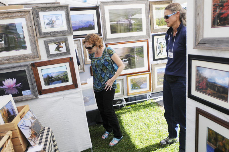 Angel Lorom of Bath looks over the photography of Johnna Haskell, right, of Carrabassett Valley.