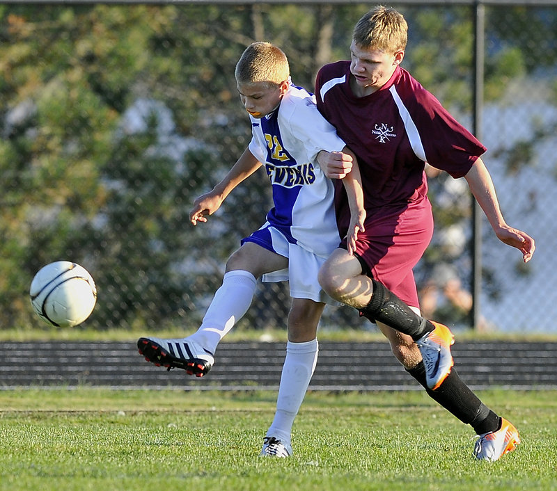 Sterling Weatherbie of Cheverus, left, sends the ball ahead while tangling with Noble’s Ben Haskell during an SMAA boys’ soccer game Tuesday. Cheverus built a 3-0 lead and held off the Knights for a 4-2 victory at Portland.