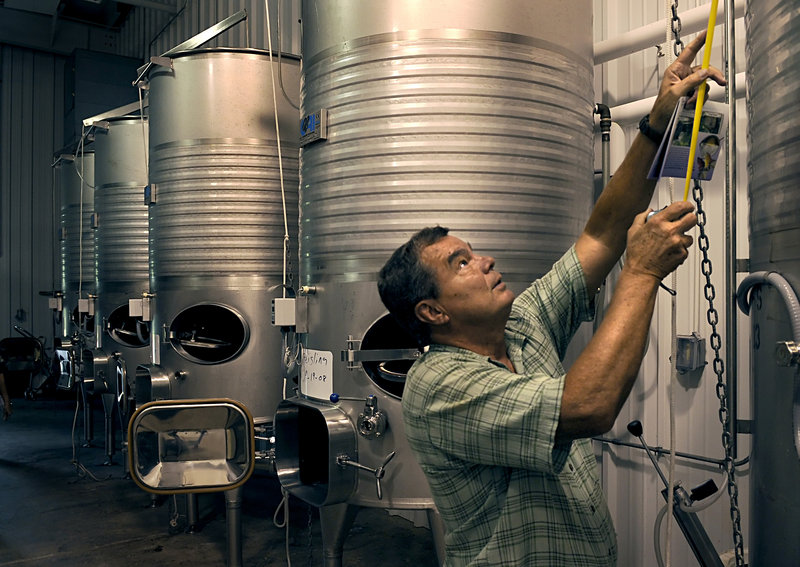 Ken Furr measures a wine vat in the Black Wolf Vineyards winery before the auction of the Dobson, N.C. property, which has been on the market for months with no buyers.