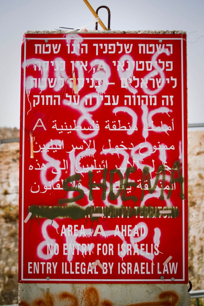 Graffiti sprayed on top of a road sign forbidding Israelis from traveling in Palestinian territory last week reads the state of Israel degraded.