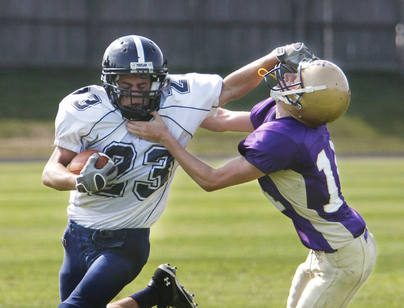 Nick Volger of Portland applies a stiff-arm to Liam Fitzgerald of Cheverus while gaining yardage Saturday during the second half of Cheverus 22-19 victory. The Stags remained undefeated.