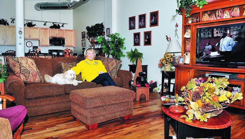 Peggy Jason relaxes in her apartment in the Hathaway building in Waterville with her dog Buffy. Jason, who worked in the Hathaway mill for 23 years on the same floor as her studio, said, “I love living here. I feel safe and secure.”